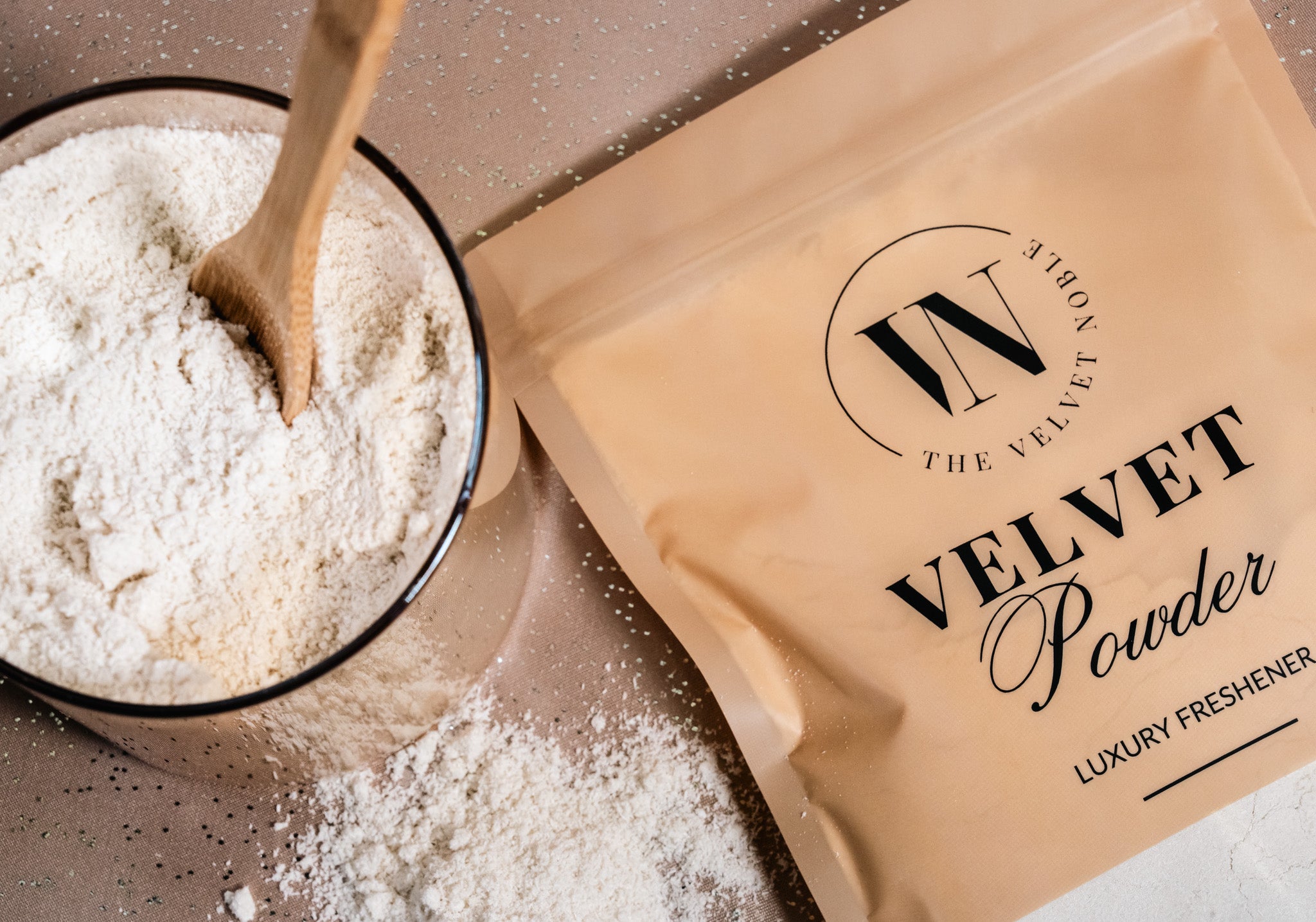 Bag of velvet powder with a wooden spoon in a bowl of powder on a neutral background
