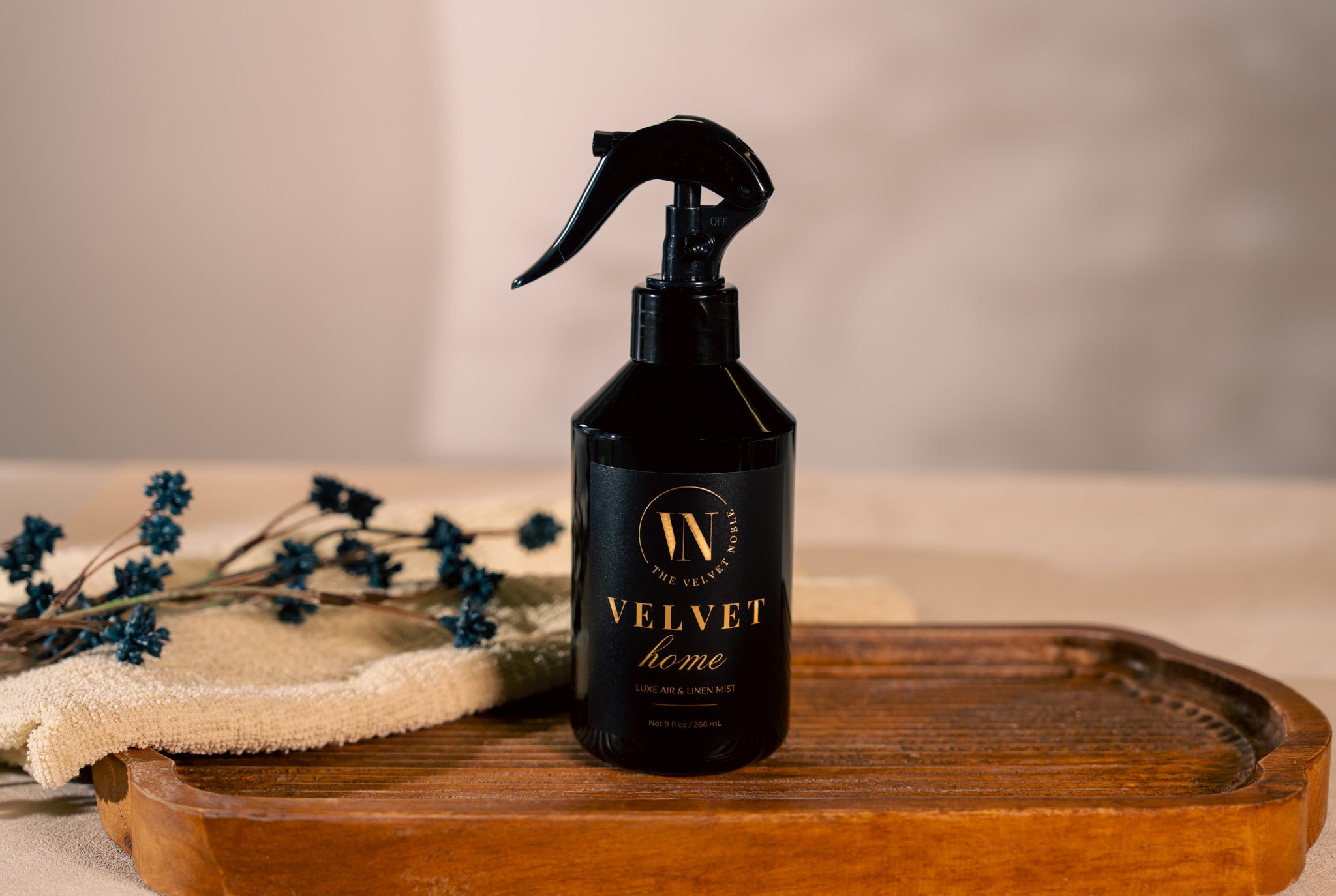 Black spray bottle labeled 'Velvet Home' on a wooden surface with a neutral background