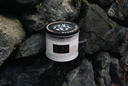 Clean Slate Candle in a glass container with a black lid on rocky terrain