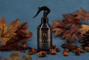A bottle of Velvet Home Air & Linen Mist on a blue background with decorative fall elements.