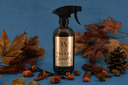 A bottle of Velvet Sparkle multipurpose spray on a blue background with decorative fall elements.