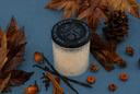 A single wick Autumn Rain candle on a blue background with decorative fall elements.