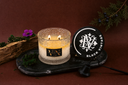 Black Vintage 2 Wick Candle with a decorative label on a dark surface with decorative elements.