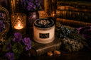 Candle with decorative label on a wooden surface with purple flowers and books in the background