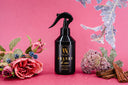 Black spray bottle labeled 'Velvet Home' on a pink background with flowers.