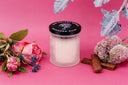 Single Wick Blushed Rain Candle on a pink background with floral elements.