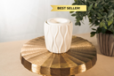 A textured, white fragrance warmer on a gold pedestal with a plant in the background. There is a "Best Seller!" label.