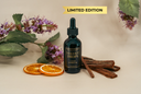 Bottle of 'Velvet Drops' with cedar, patchouli, and oranges on a neutral background
