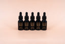 Five black bottles labeled 'Velvet Drops' on a beige background