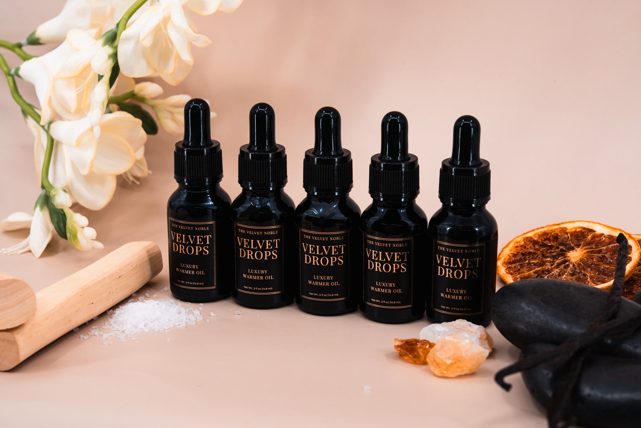 Set of 'Velvet Drops' dropper bottles on a table with decorative items.