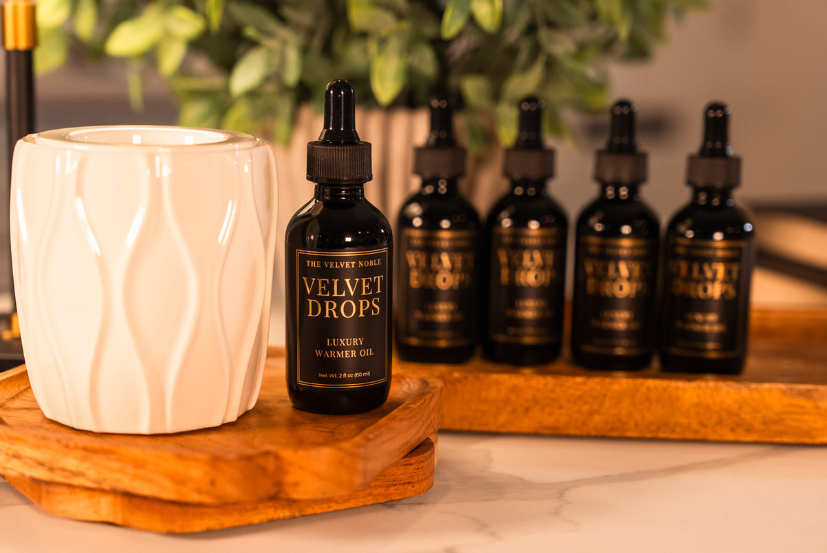 Bottle of Velvet Drops on a wooden tray with a white ceramic container and more bottles in the background.