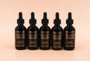 Five bottles of Velvet Drops luxury warmer oil on a beige background