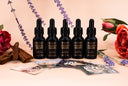5 mini bottles of Velvet Drops with floral elements and 5 fragrance cards laid in front of them featuring Washed Amber, Blushed Rain, Black Velvet, Morning Mist, and Velvet Ease.