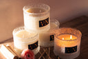 Set of lit candles with decorative labels on a wooden surface.