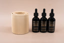 Three bottles of Velvet Drops with a tan fragrance warmer on a beige background