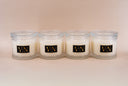 Four candle jars with decorative lids on a beige background