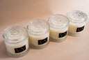 Four candle jars with decorative lids on a beige background