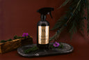 Black spray bottle labeled 'Velvet Sparkle' on a dark surface with greenery and flowers.