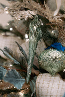 Green transparent glass ornament on a green and golded accented Christmas tree. 