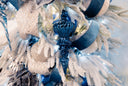 A blue finial ornament, with a crystal pendant drop hanging from the bottom on a white and silver Christmas tree.