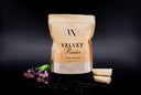 A stand-up pouch of Velvet Powder luxury freshener by The Velvet Noble, styled on a dark background with patchouli flowers, black pepper, and scattered vanilla beans.