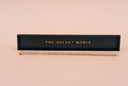A clear and gold luster wand with corresponding black and gold "THE VELVET NOBLE" resting tray.