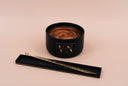A Velvet Luster Wickless candle and accompanying luster wand with a black and gold THE VELVET NOBLE resting tray