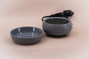 A grey textured fragrance warmer shown with its matching dish and black power cord on a solid beige background.
