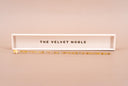 A clear and gold luster wand with a white and gold "THE VELVET NOBLE" resting tray.