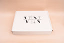 A white rectangular box with the black printed logo 'VN | THE VELVET NOBLE' on top, photographed on a smooth warm beige background.