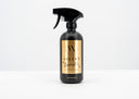 Black spray bottle with gold label on a white background