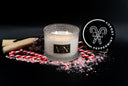 A lit scented candle in a clear textured glass jar with a black and gold label reading VN, styled with candy canes, crushed candy cane pieces, and a round black lid printed with a candy cane motif and the words 'VN PEPPERMINT LEGACY' on a black background.