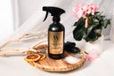 Black spray bottle labeled 'Velvet Sparkle' on a wooden tray with decorative items.