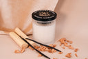 Vanilla-scented candle with vanilla beans and wood on a beige background