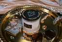 Velvet Stacks 2-Wick Candle on a gold tray with Jewelry, Cash, and Sunglasses