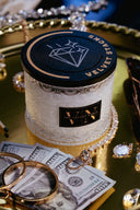 Velvet Stacks 2-Wick Candle on a gold tray with Jewelry, Cash, and Sunglasses
