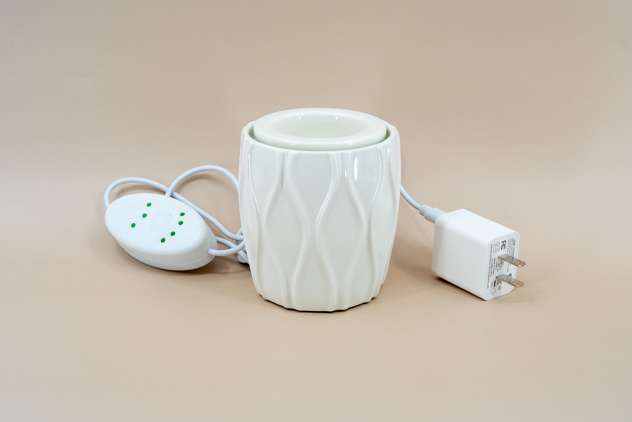 A ceramic fragrance warmer on a beige background.