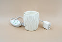 A ceramic fragrance warmer on a beige background.
