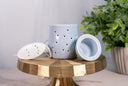 Light Blue Ceramic Fragrance Warmer on a golden surface with a plant in the background. The warmer dish & fragrance warmer controls are on display.
