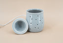 Light blue fragrance warmer on a beige background and warmer dish on display.