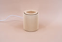 Light brown fragrance warmer with ribbed texture on a beige background