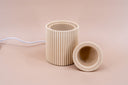 Beige light brown fragrance warmer with ribbed design on a beige background.