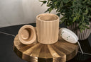 Light Brown Fragrance Warmer with controls on a golden pedestal with a plant in the background. 