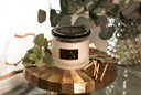 Velvet Ease Candle with Mint and matches on a golden surface with Eucalyptus in the background.