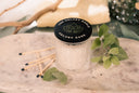 Velvet Ease Single Wick Candle on a textured surface with leaves and matches.