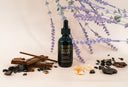 Bottle of 'Velvet Drops' with lavender flowers and other natural elements on a light background