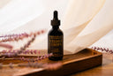 Bottle of Velvet Drops on a wooden tray with lavender flowers in the background