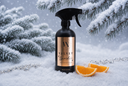 A black trigger spray bottle labeled 'Velvet Sparkle' stands in snow with evergreen branches and orange slices around it, suggesting a winter-themed room spray or moisturizer.