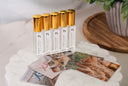 Set of small bottles with gold caps on a decorative surface with fragrance cards
