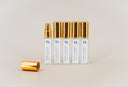 Set of five mini sprays bottles with gold caps on a beige background